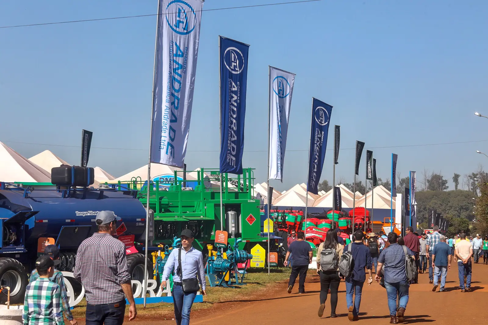 Visitantes caminham entre estandes e bandeiras de fabricantes de máquinas na Agrishow, em Ribeirão Preto