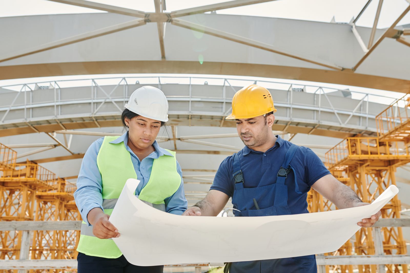 Dois engenheiros de capacete analisam um projeto em uma obra, ilustrando a cultura de segurança do trabalho que a SIPAT reforça uma vez por ano