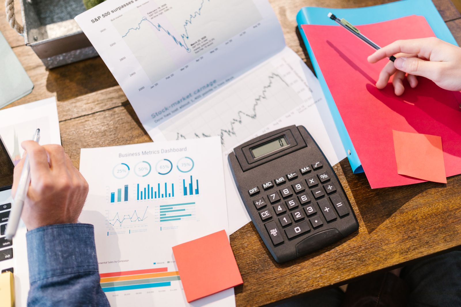 Calculadora, anotações e gráficos sobre uma mesa, ilustrando planejamento abordado por palestrantes de educação financeira
