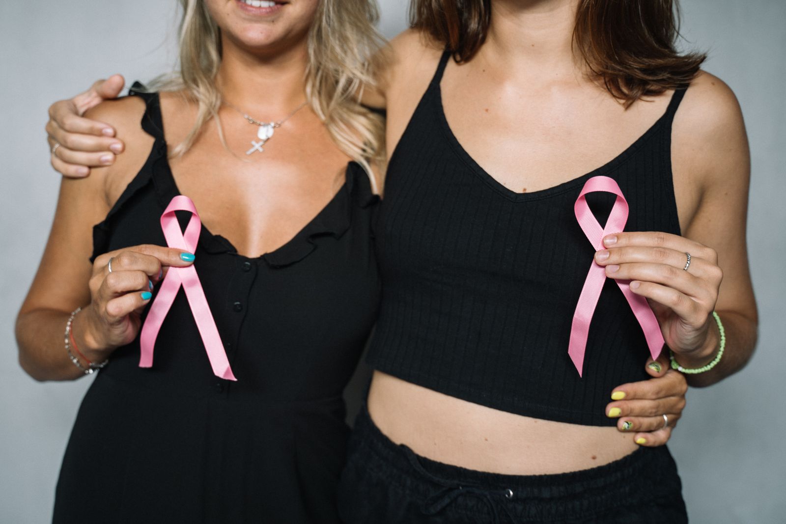 Duas mulheres seguram laços de conscientização para uma palestra de Outubro Rosa na empresa