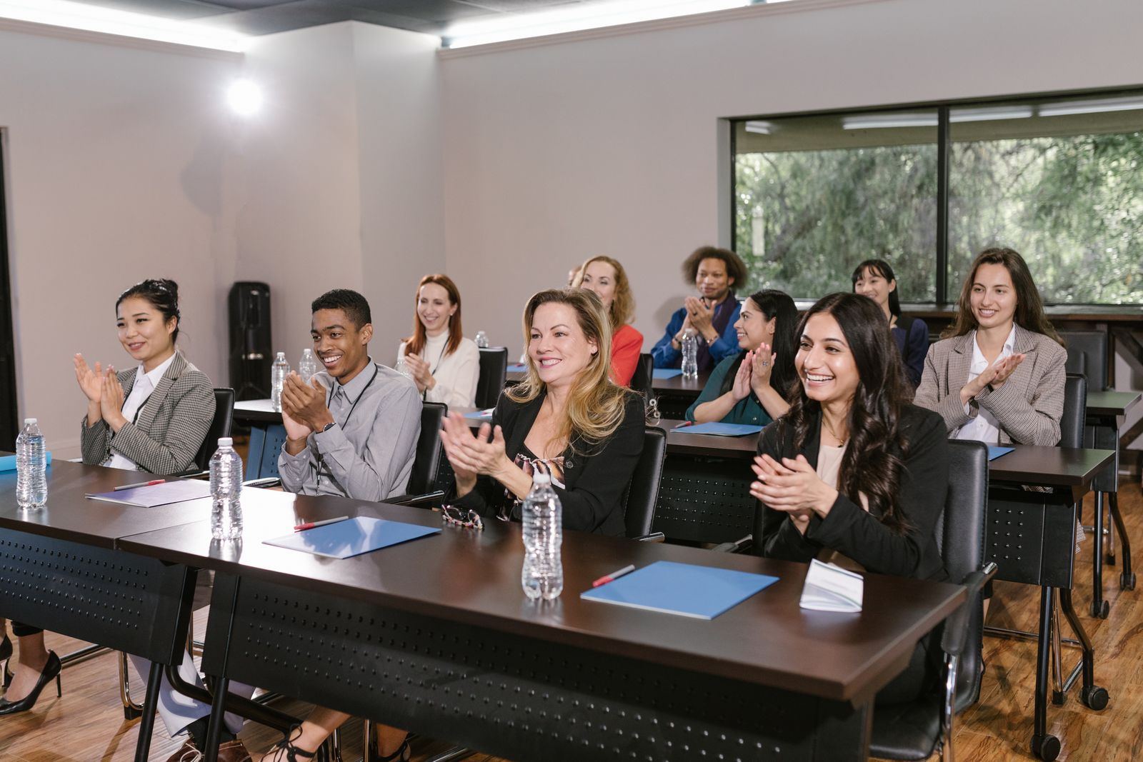 Equipe comercial aplaudindo em auditório durante convenção de vendas com palestrante